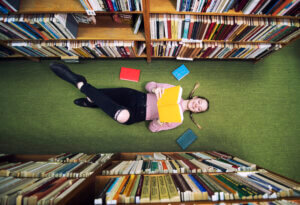 student lying on her back reading in the Lirbary