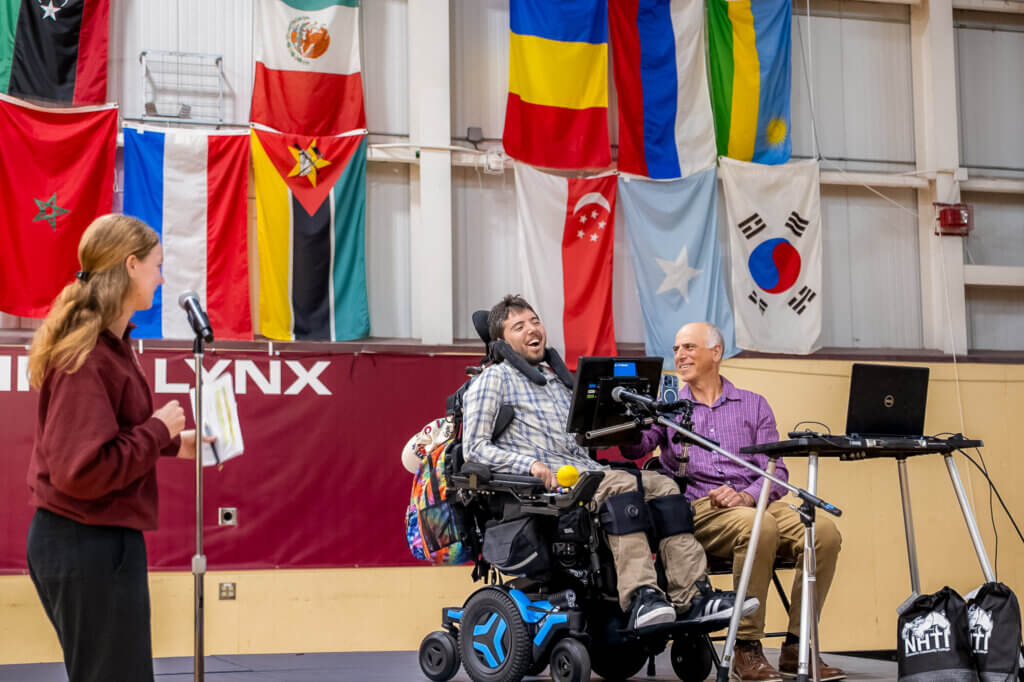 Three speakers onstage, keynote speaker Samuel Habib uses a wheelchair